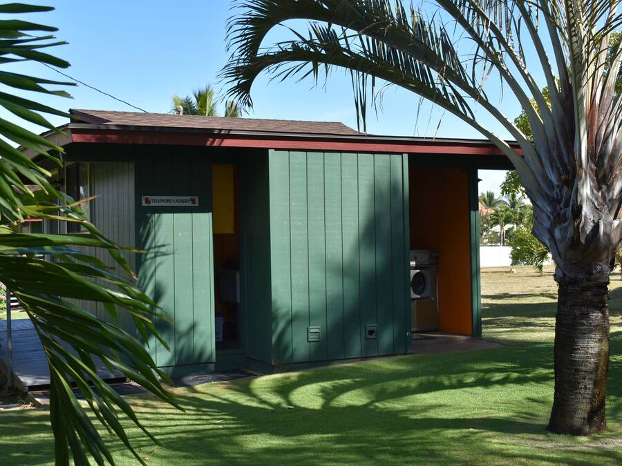A small, single-story building with a green exterior and a red roof, labeled as a telephone laundry service.