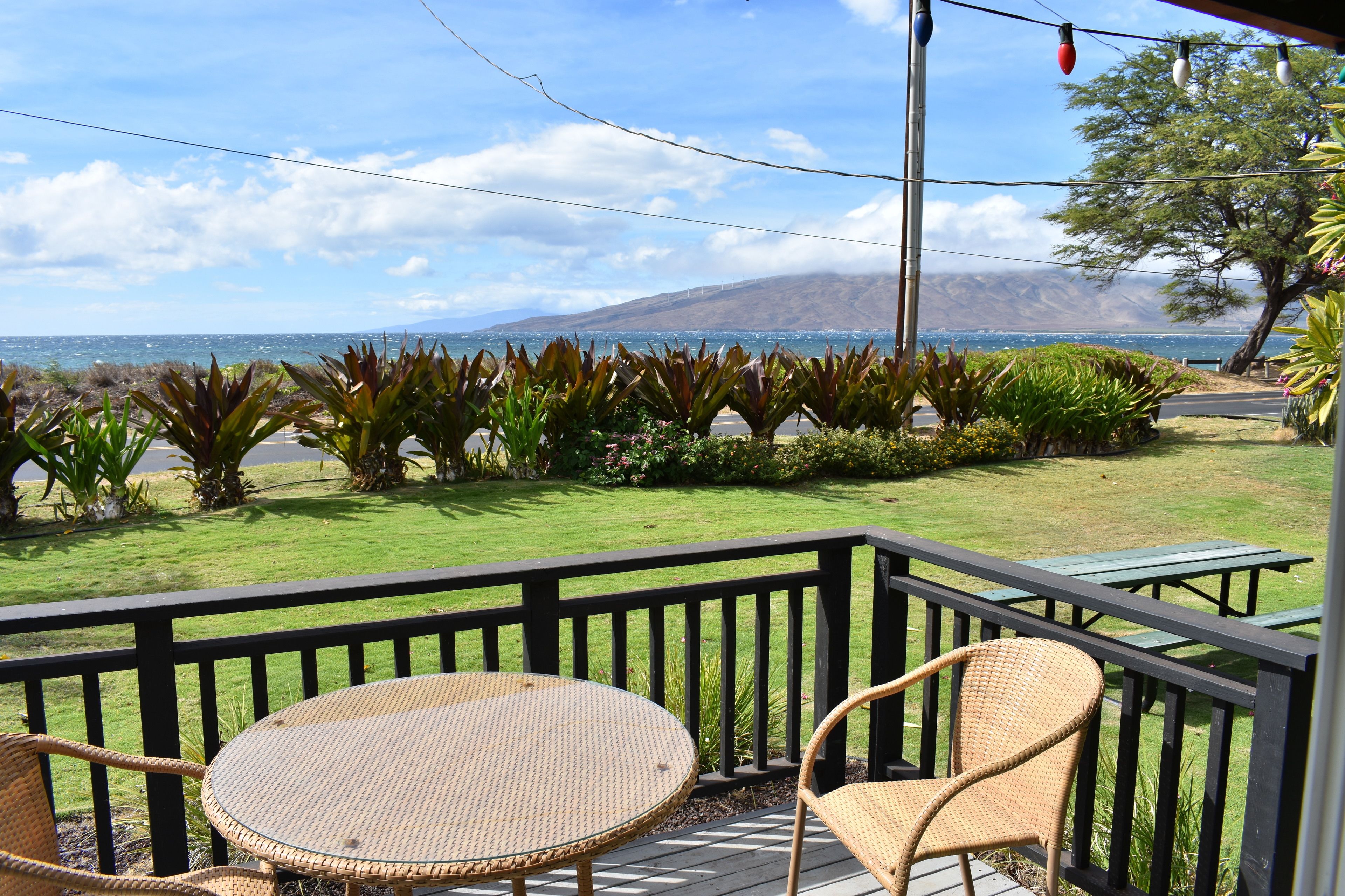 Eine Terrasse mit Korbmöbeln und Blick aufs Meer.
