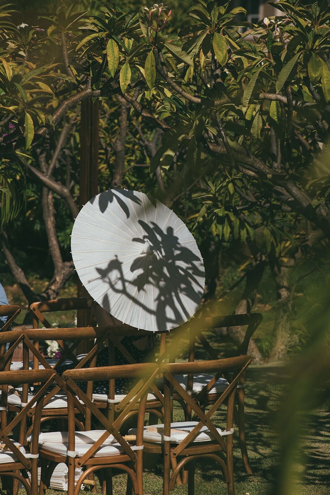 Outdoor wicker chairs arranged in a semi-circle with a large white umbrella providing shade.