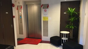 A hotel lobby with a reception desk, a red carpet, a plant, and a wall-mounted elevator. - ST Signature Bugis Beach (Singapore)