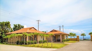 Two buildings with a flat roof, surrounded by palm trees and a clear sky.