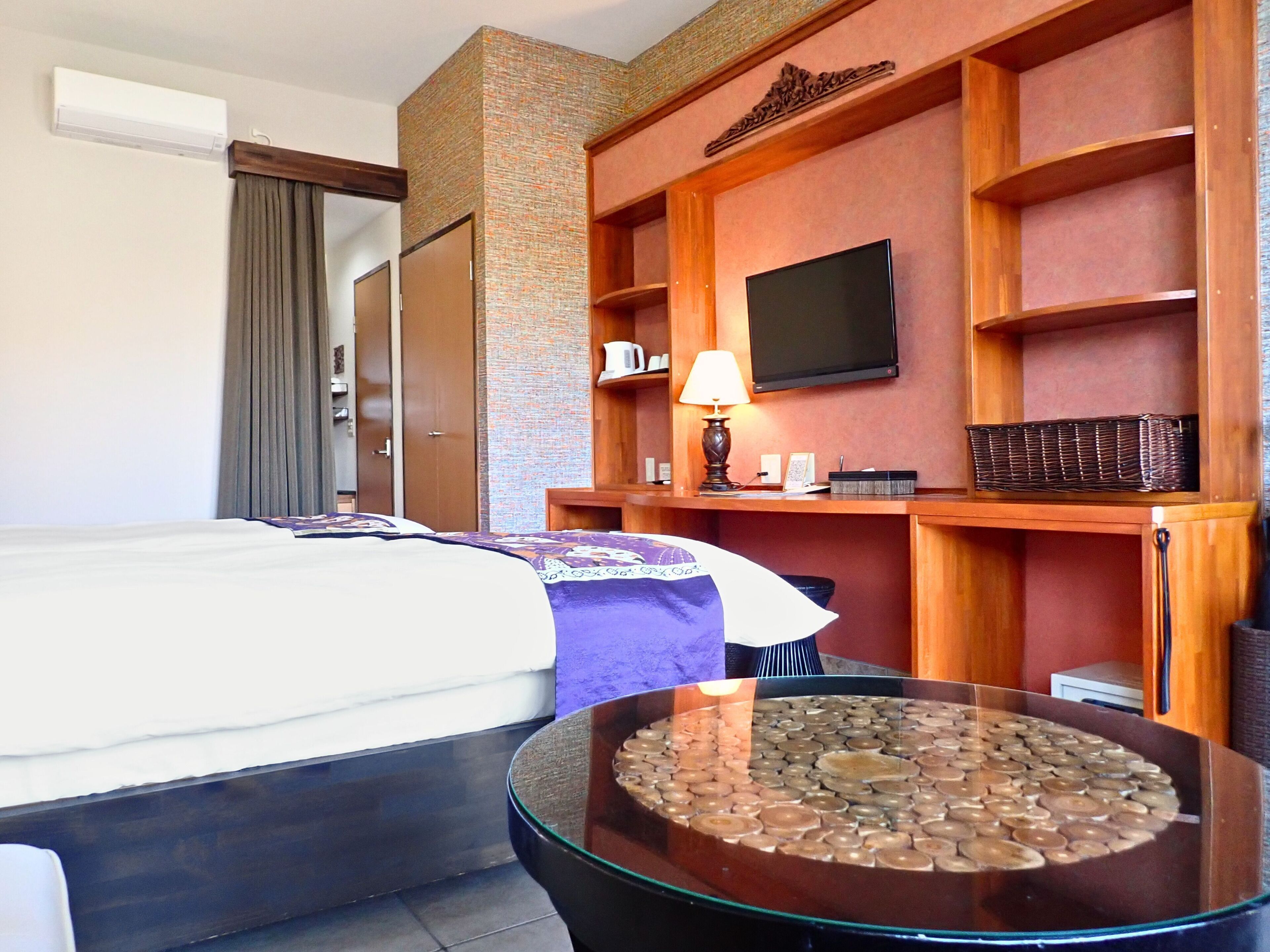 Una habitación de hotel con una cama, un escritorio con lámpara, un televisor y un adorno en la pared.