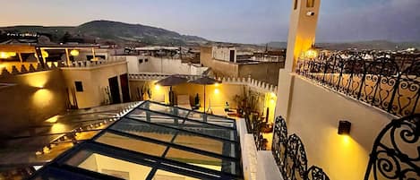 Une terrasse sur le toit, dotée d’une structure en verre, d’une rampe en fer forgé décorative et d’une tour avec une horloge.