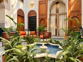 Un patio con una fuente, zona de estar y puertas ornamentadas.