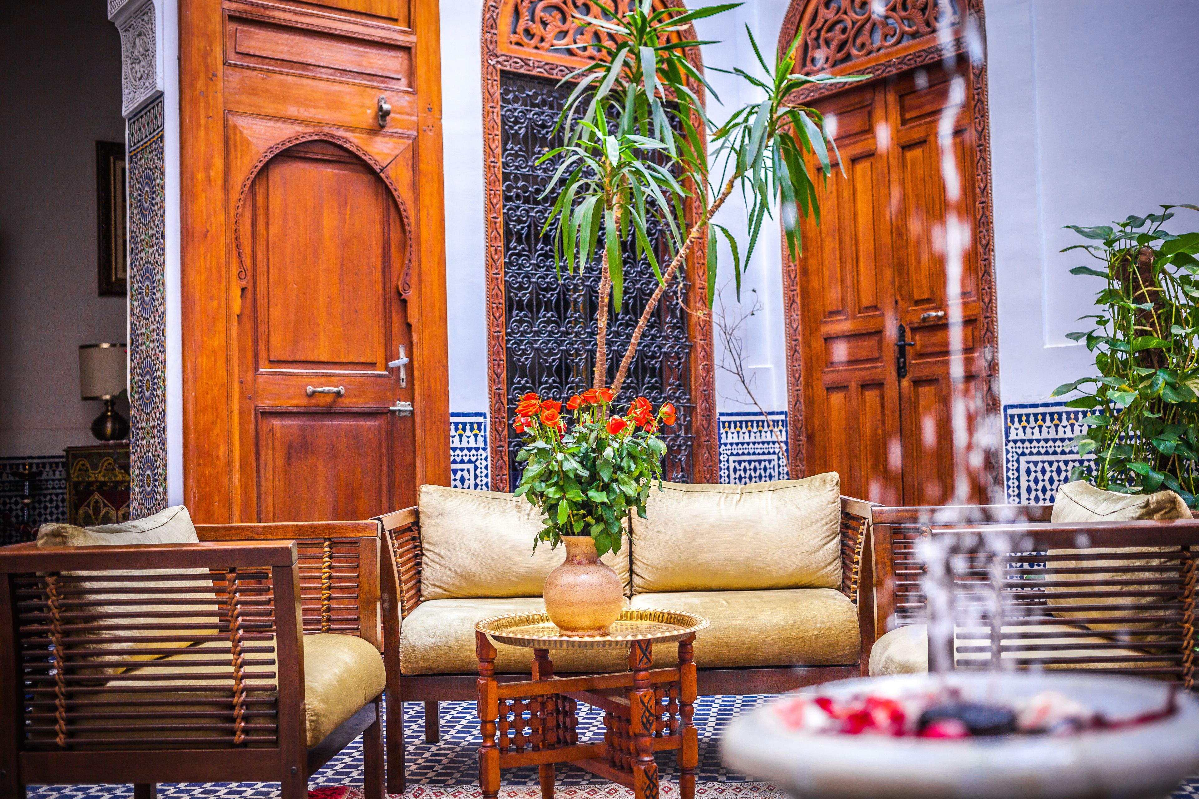 Un interior tradicional marroquí con puertas de madera, un sofá y una mesa con un jarrón de flores.