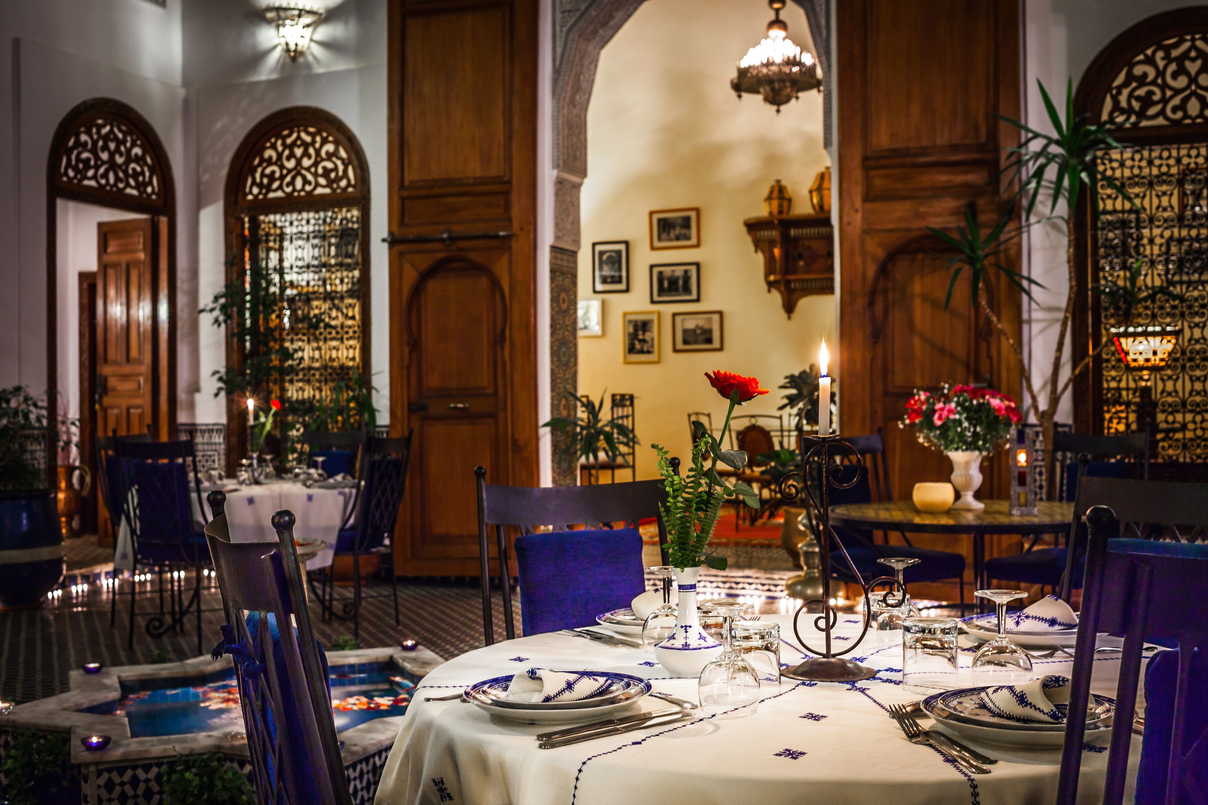 Uma sala de jantar com mesas postas para refeição, com decoração tradicional e ambiente acolhedor.