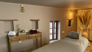A bedroom with a bed, a wooden dresser, a mirror, and a window with curtains.