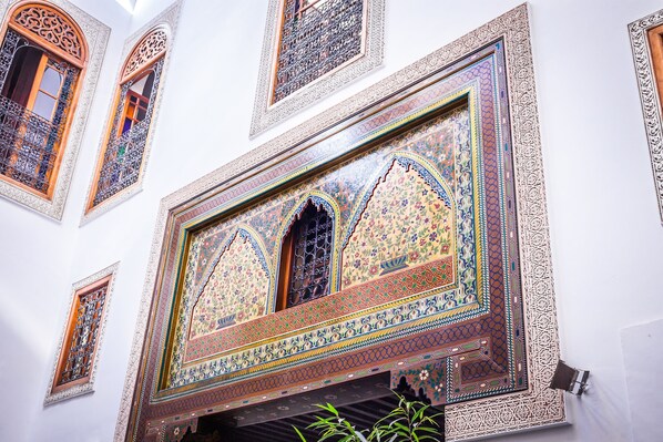 Detalle de una pared con intrincados diseños geométricos y una obra de arte grande enmarcada.