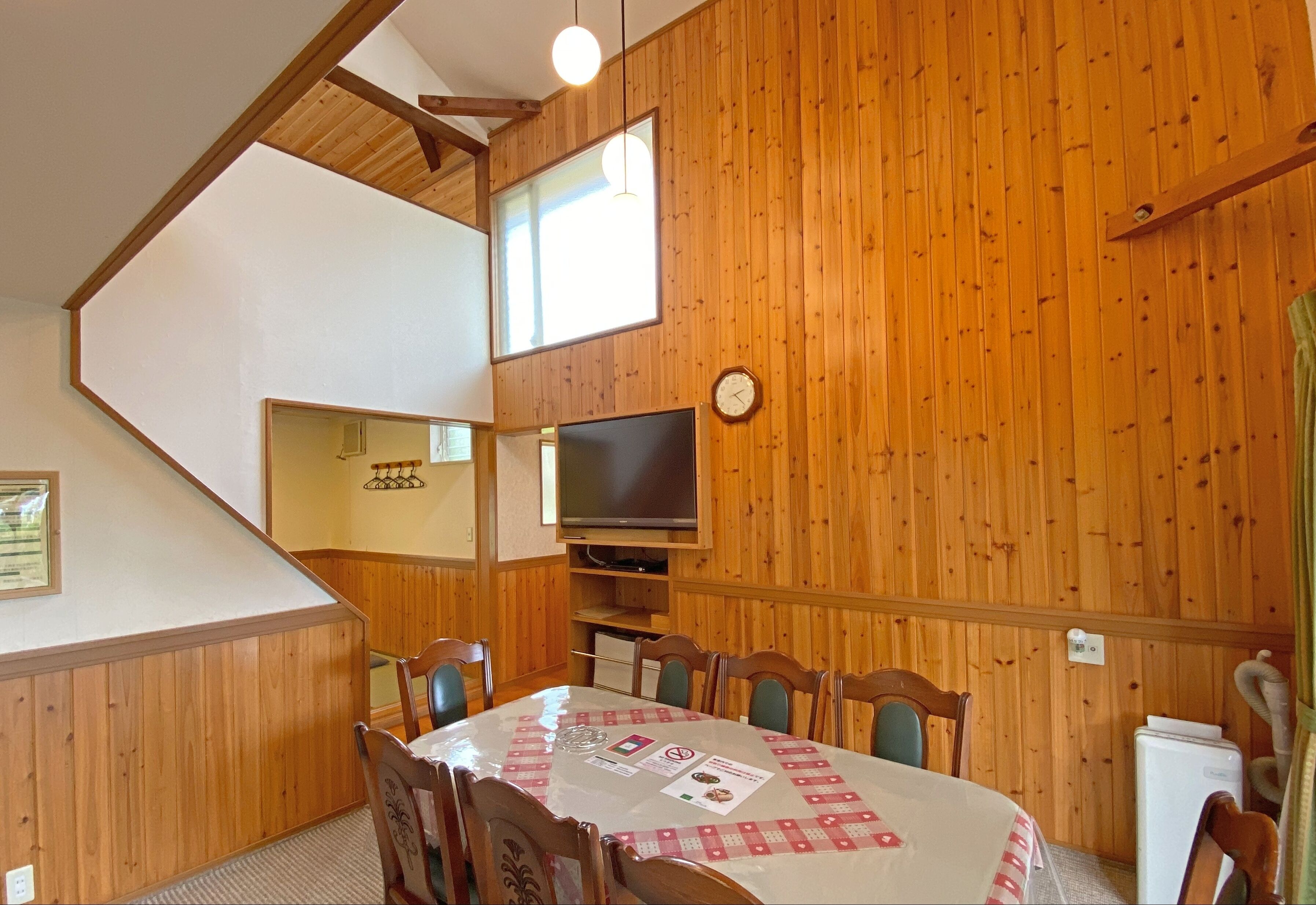 A dining area with a wooden interior, a television mounted on the wall, and a table with chairs.