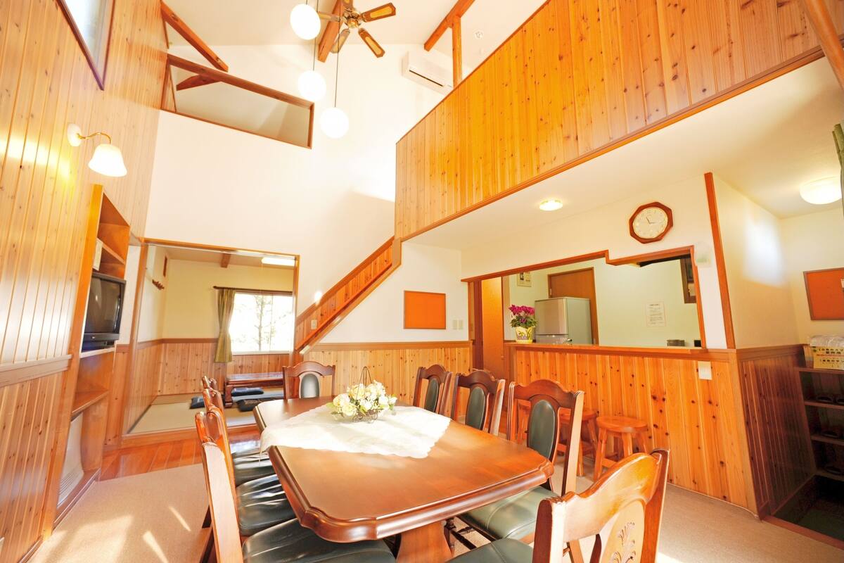 Un coin repas avec une table et des chaises en bois, un ventilateur de plafond et une horloge au mur.