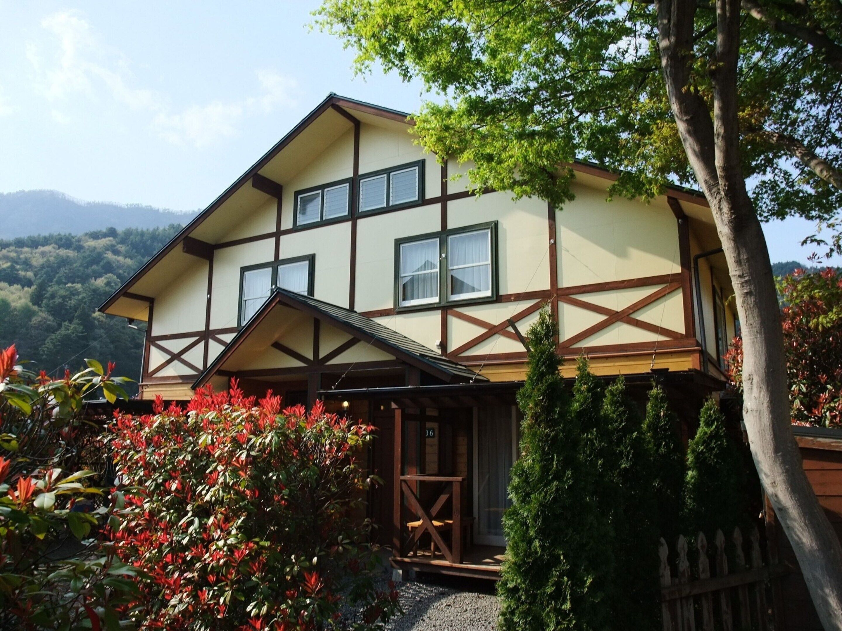 A traditional chalet with a gabled roof, a wooden porch, and a view of the surrounding hills.