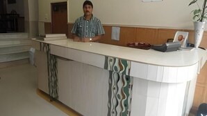 A reception desk with a patterned design, a whiteboard on the wall, and a plant in a vase. - Roxy Dx (New Delhi)