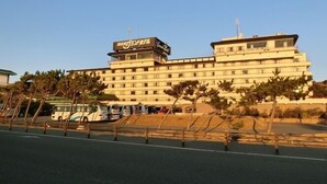 Un hotel de varios pisos con fachada plana, numerosas ventanas y un letrero en la parte superior.