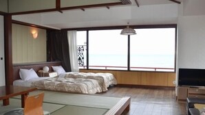 Una habitación con cama, futón, televisión y vista al mar.