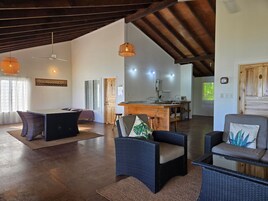 Amplia sala de estar con mesa de comedor, dos sofás, zona de cocina y ventilador de techo.