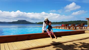 Una piscina al aire libre, sillones reclinables de piscina