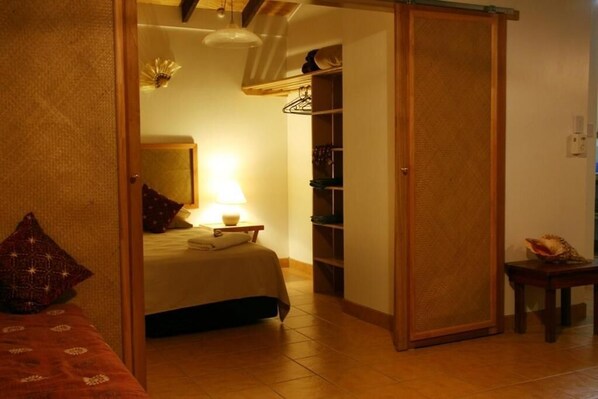 Un dormitorio con cama, mesita de noche, lámpara y armario.