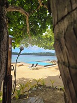A beach view with a wooden deck, lounge chairs, and a pool.