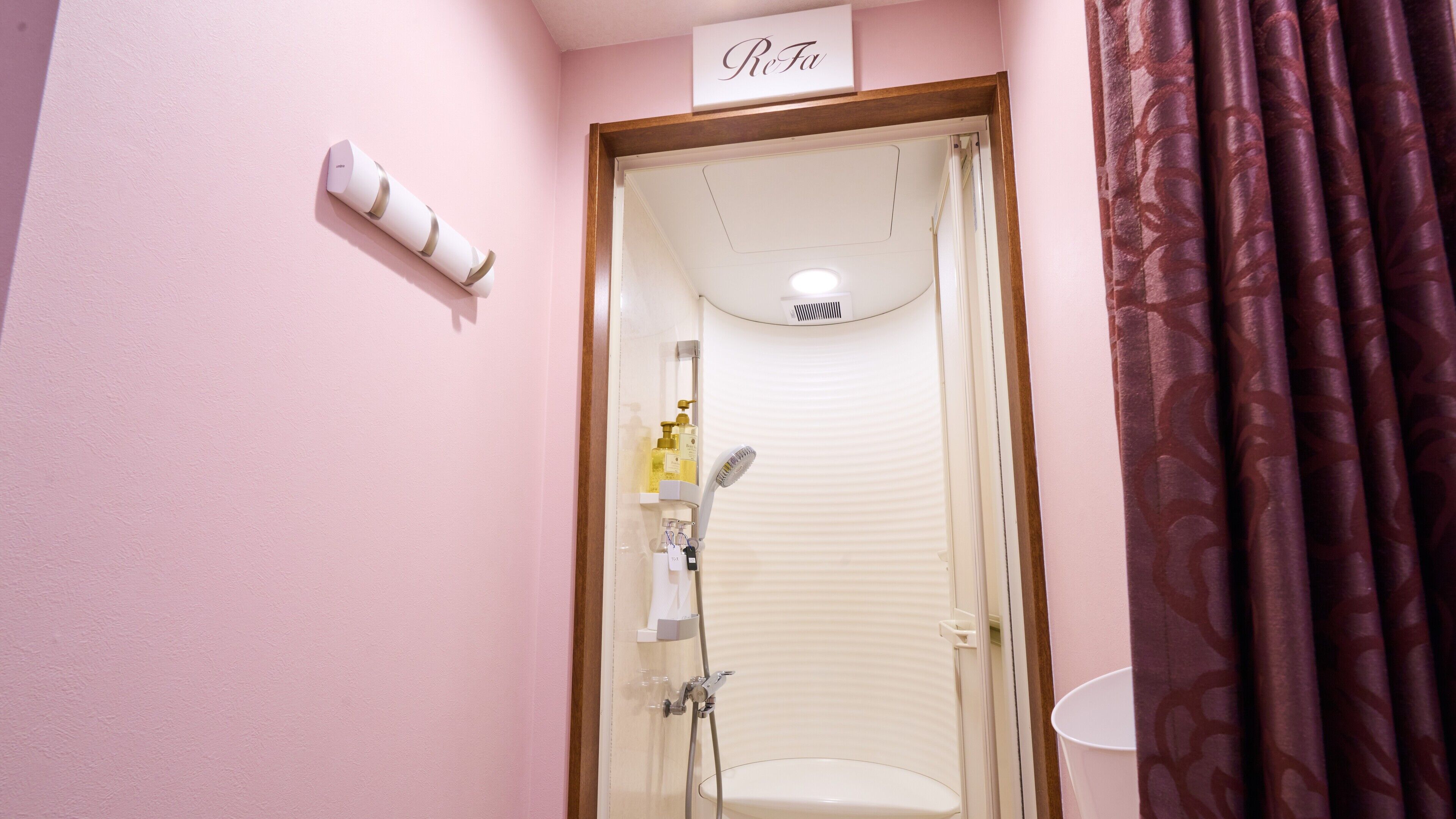 Un baño con ducha, inodoro y perchero para toallas.