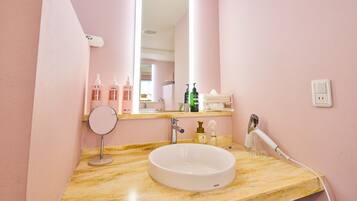 Une salle de bain avec un lavabo en marbre, un miroir, un sèche-cheveux et divers produits de toilette disposés sur le comptoir.