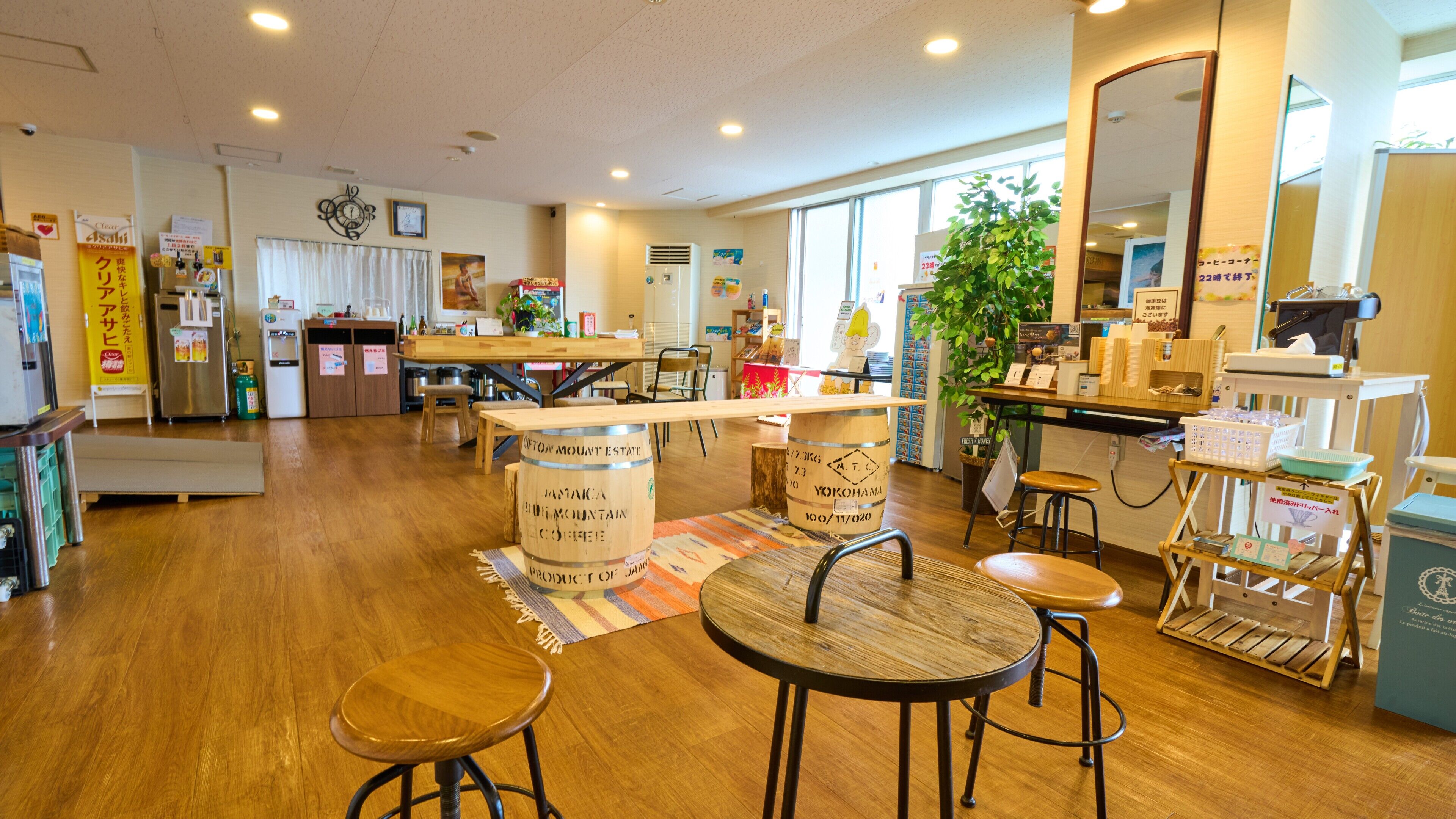 Un café spacieux, doté de meubles en bois, d’un îlot central avec une machine à café et d’une grande fenêtre laissant entrer la lumière naturelle.