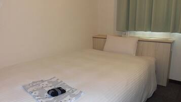 Cama arrumada com colcha branca e toalha dobrada estampada.