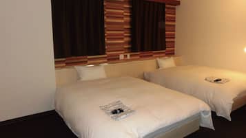 Una habitación de hotel con dos camas individuales, un cabecero a rayas y un ventanal con cortinas.