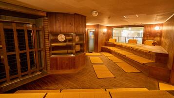 A sauna room with wooden walls, a clock, and benches.