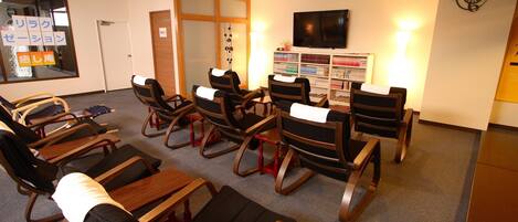 A room with several massage chairs, a television, and a bookshelf with magazines.