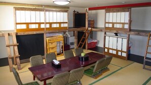 Una habitación tradicional japonesa con suelo de tatami, una mesa baja con cojines y puertas correderas shoji.