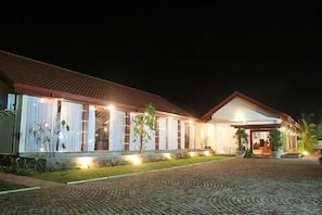 A building with a tiled roof, large windows, and a paved entrance area.