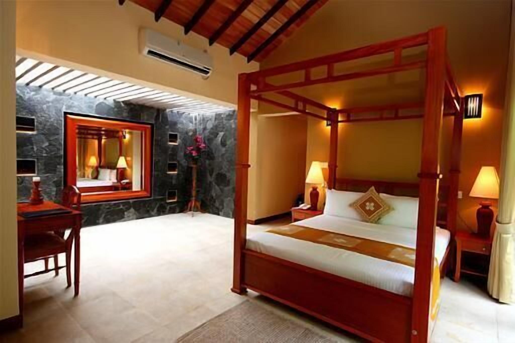 A four-poster bed with a stone wall and a mirror.