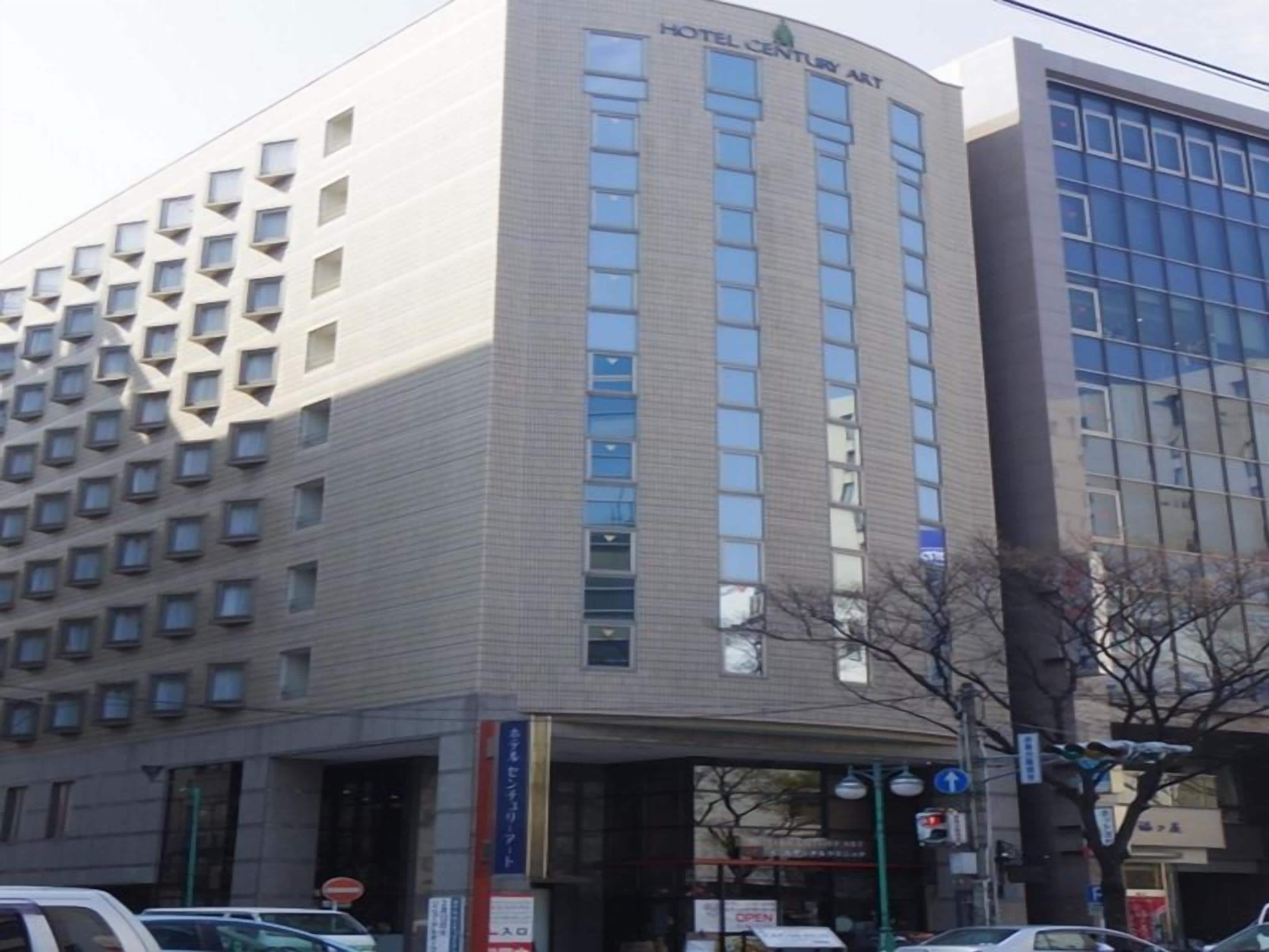 En bygning i flere etager med moderne arkitektur, der har en markant indgang med en glasfacade og et skilt, der angiver, at det er et hotel.