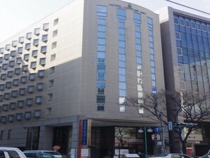 A multi-story building with a modern architectural design, featuring a prominent entrance with a glass facade and a sign indicating it is a hotel. - Century Art (Fukuoka)