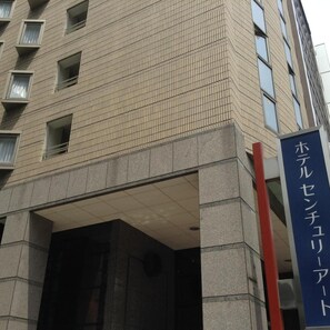 A multi-story building with a tiled facade and a sign indicating a hotel or similar establishment. - Century Art (Fukuoka)