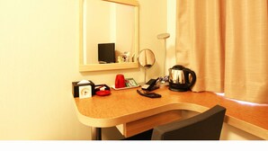 A compact hotel room with a wooden desk, a small television, a mirror, a kettle, and a clock. - Century Art (Fukuoka)