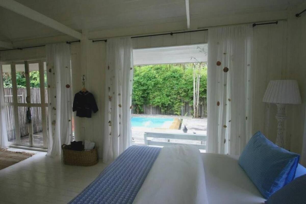 Quarto com cama, vista para uma piscina e porta que dá para o exterior.