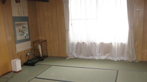 A room with tatami flooring, a wooden wardrobe, a framed picture, and a window with sheer curtains. - Kyo no Machiya Uenoya (Kyoto)
