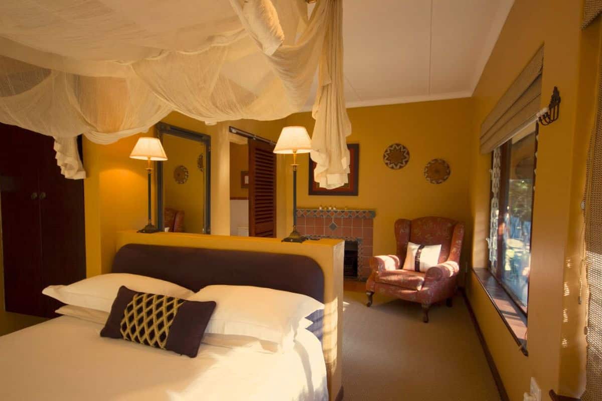 Une chambre à coucher avec un lit, une chaise, une table de chevet et une fenêtre.