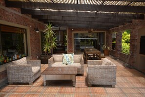 An outdoor patio area with wicker furniture, a brick wall, and potted plants.