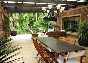 An outdoor patio with a dining table, chairs, and a chandelier.