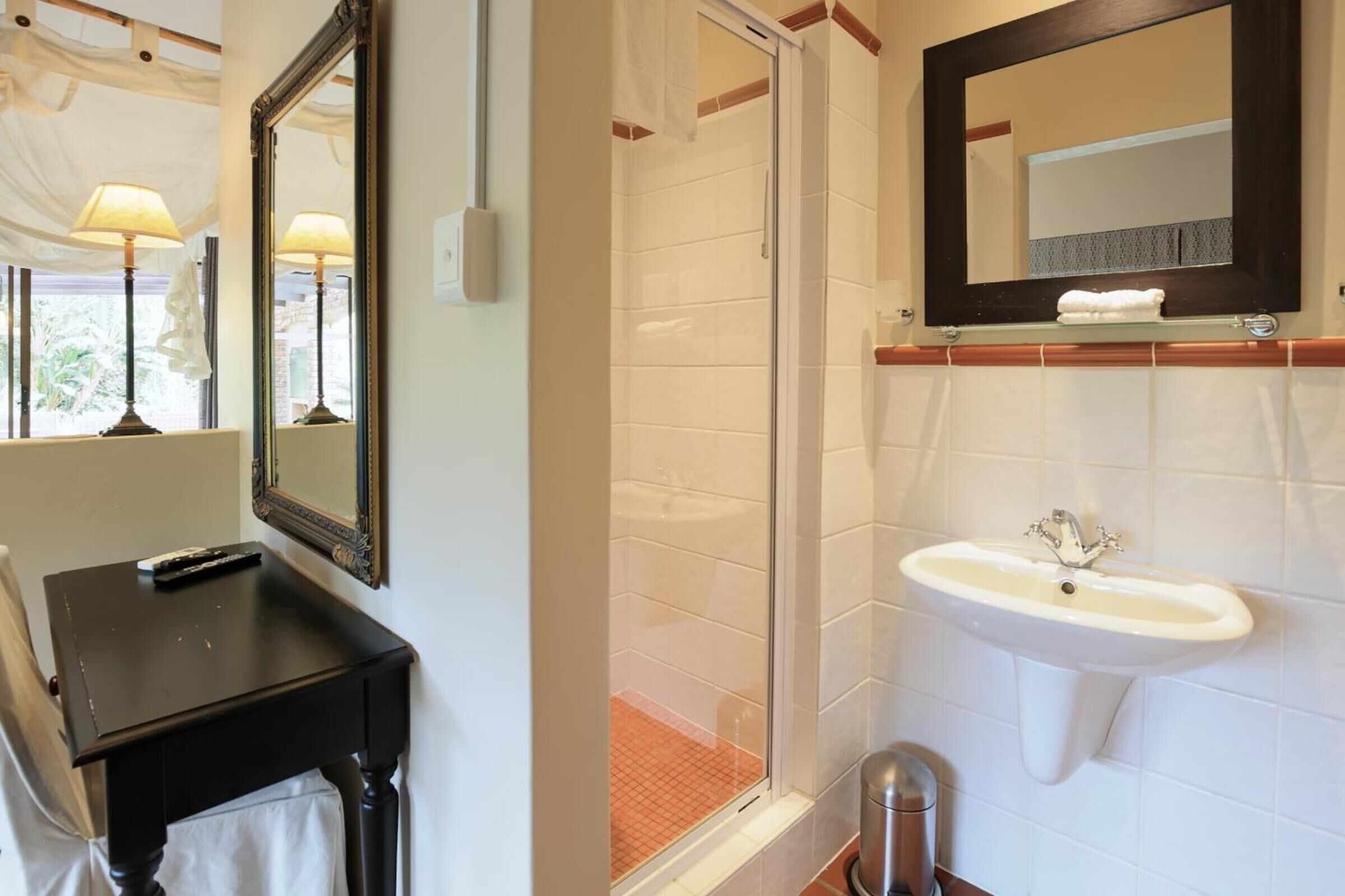 Un bagno con un mobile lavabo nero, un lavandino bianco, uno specchio e uno sporto doccia in vetro.