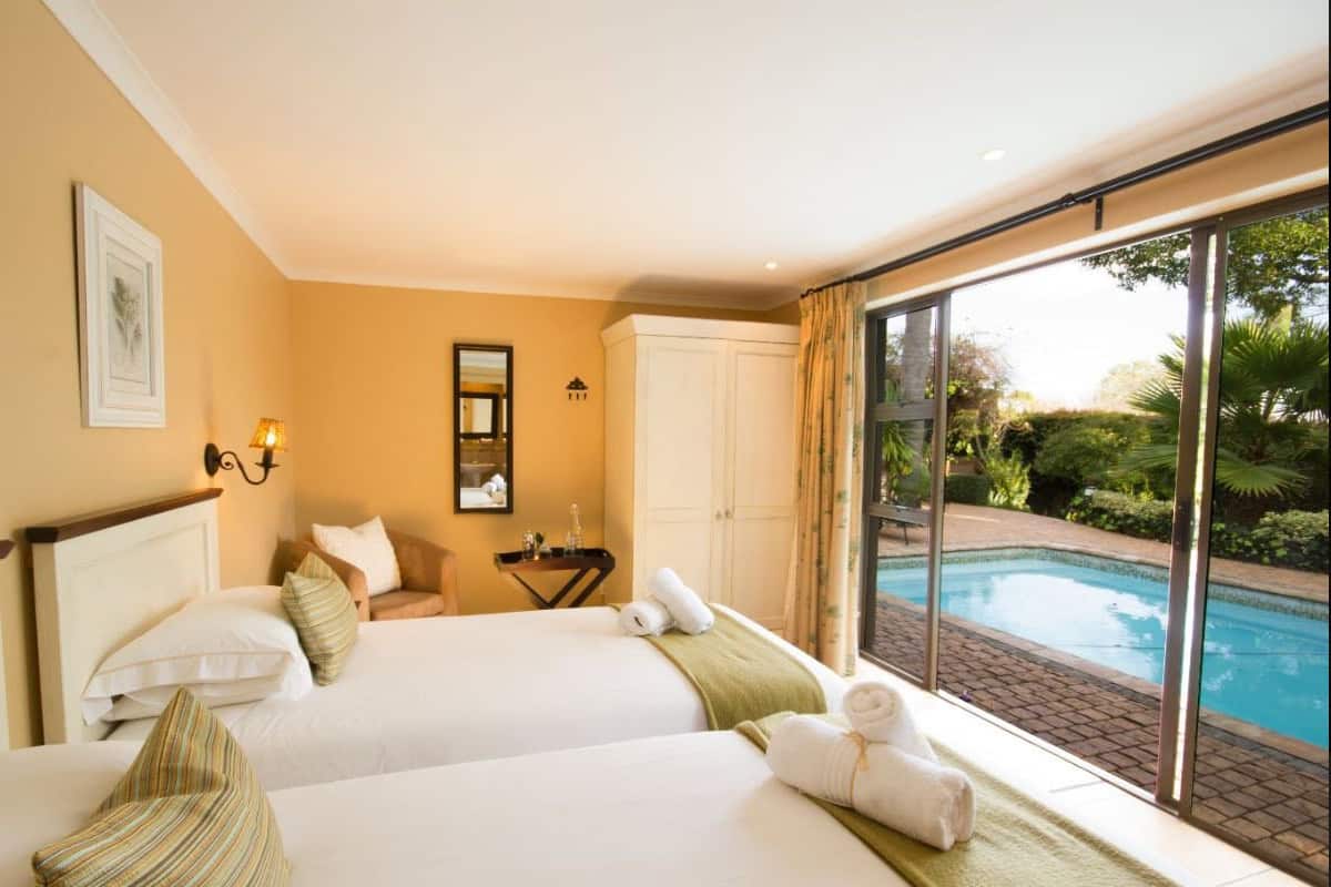 Une chambre d’hôtel avec deux lits, une vue sur une piscine et une grande fenêtre.