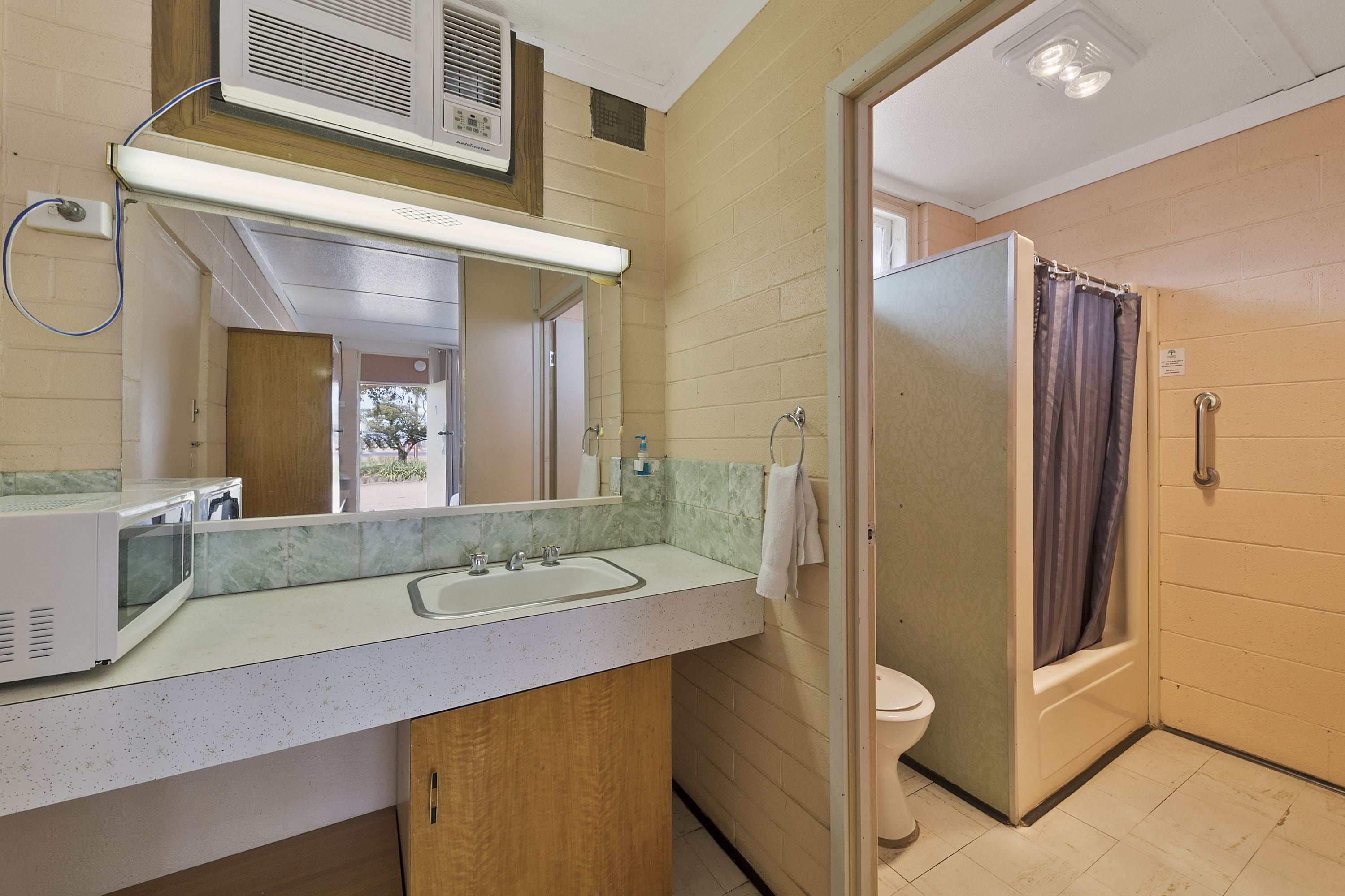 A bathroom with a shower, toilet, and a sink with a mirror.