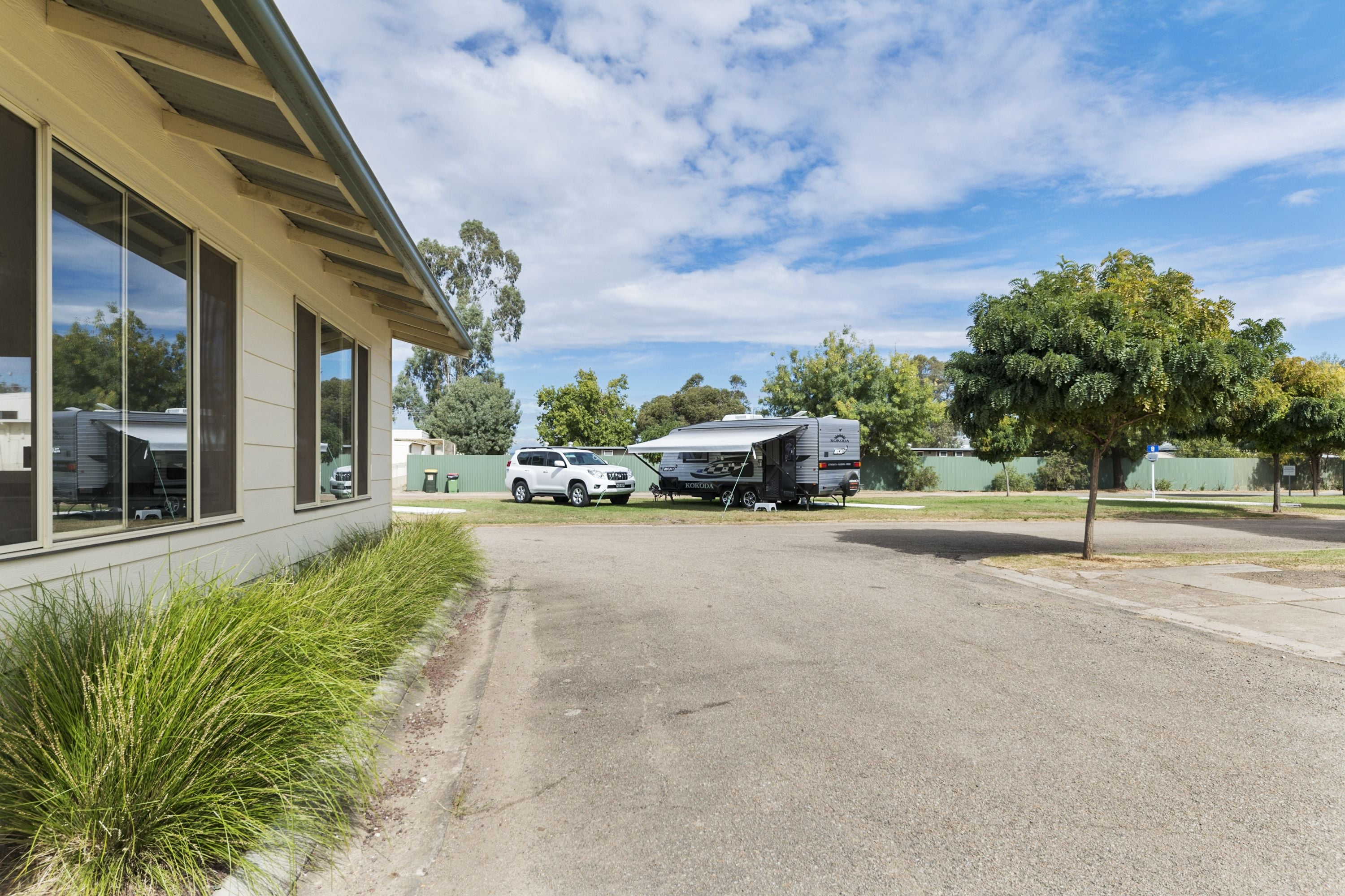 A building with large windows, a paved driveway, and a parked RV in the background.
