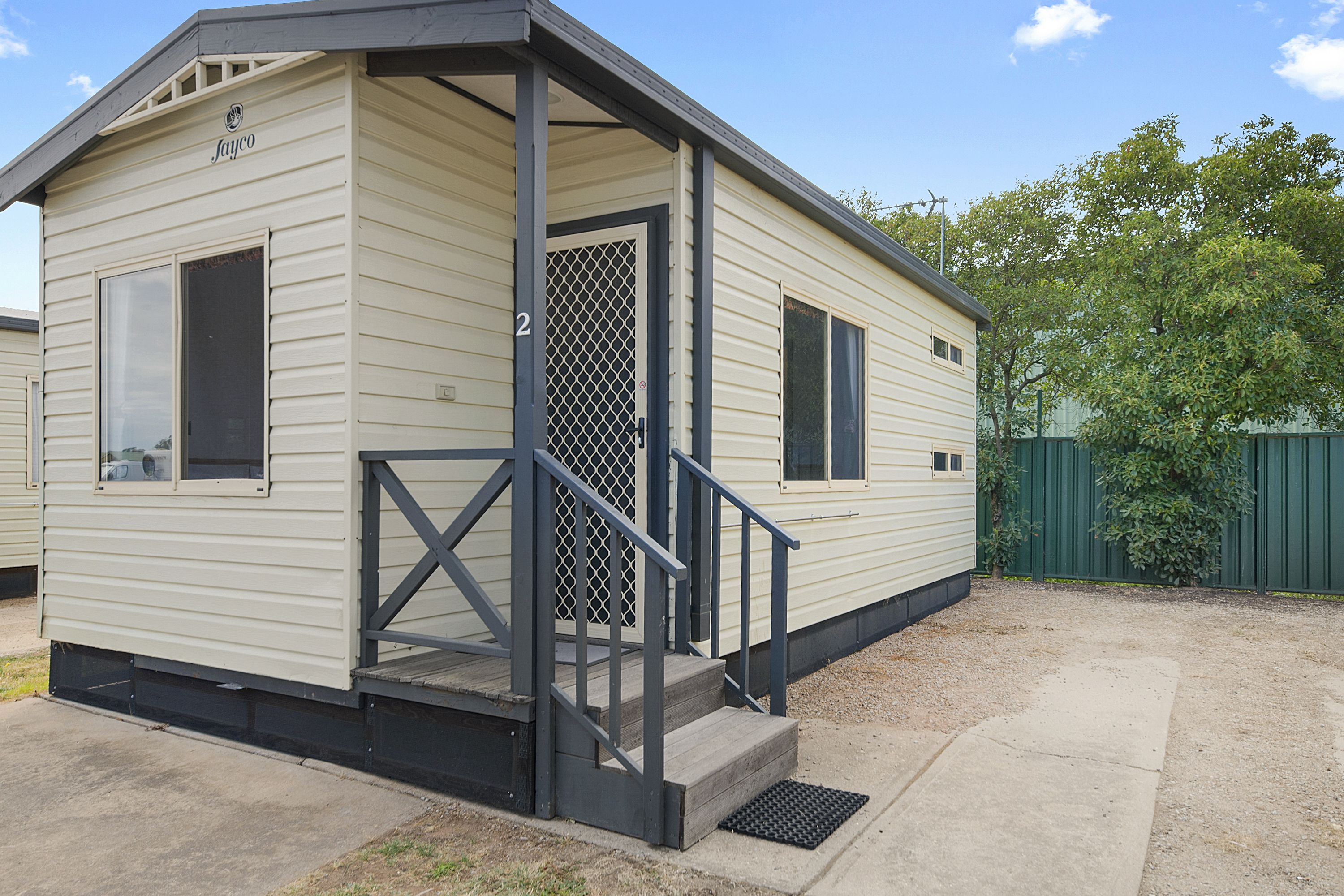 A small, single-story mobile home with a porch and a metal staircase.