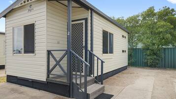 A small, single-story mobile home with a porch and a metal staircase.