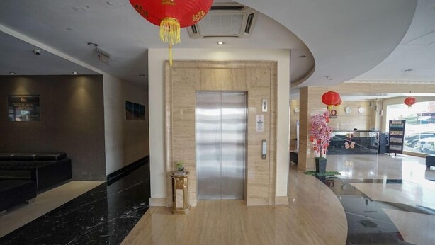 A modern hotel lobby with a reception desk, a marble floor, a wooden wall, and an elevator.