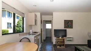 A modern kitchen with a dining area, a TV, and a small seating space. - Ashleigh Court Motel (Blenheim)