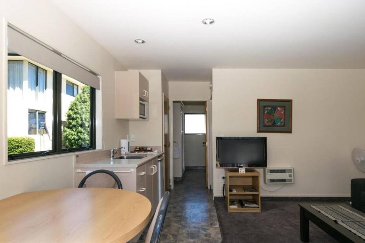 A modern kitchen with a dining area, a TV, and a small seating space.